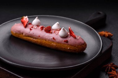 Koyu dokulu arka planda çilekli kremalı tatlı ekler veya profiterol.