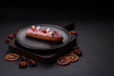 Koyu dokulu arka planda çilekli kremalı tatlı ekler veya profiterol.