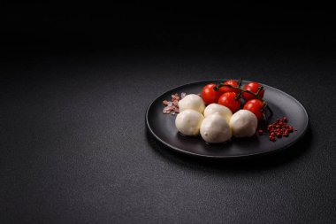 Lezzetli taze mozzarella peyniri domatesli, tuzlu ve baharatlı koyu beton arka planda.