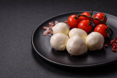Lezzetli taze mozzarella peyniri domatesli, tuzlu ve baharatlı koyu beton arka planda.