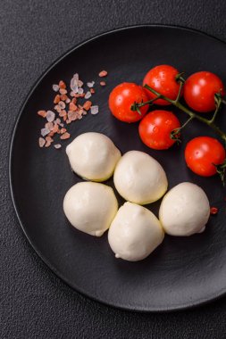 Lezzetli taze mozzarella peyniri domatesli, tuzlu ve baharatlı koyu beton arka planda.