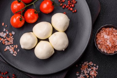 Lezzetli taze mozzarella peyniri domatesli, tuzlu ve baharatlı koyu beton arka planda.