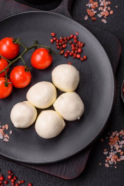 Lezzetli taze mozzarella peyniri domatesli, tuzlu ve baharatlı koyu beton arka planda.