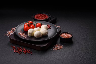 Lezzetli taze mozzarella peyniri domatesli, tuzlu ve baharatlı koyu beton arka planda.