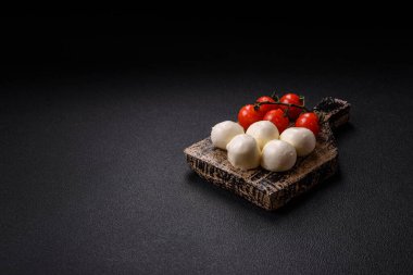 Lezzetli taze mozzarella peyniri domatesli, tuzlu ve baharatlı koyu beton arka planda.