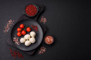 Lezzetli taze mozzarella peyniri domatesli, tuzlu ve baharatlı koyu beton arka planda.