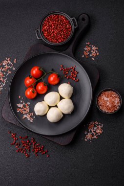 Lezzetli taze mozzarella peyniri domatesli, tuzlu ve baharatlı koyu beton arka planda.