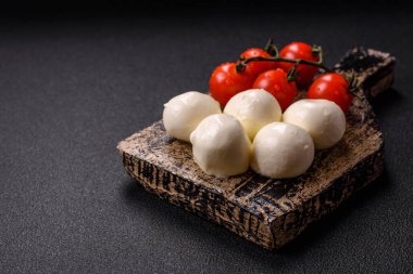 Lezzetli taze mozzarella peyniri domatesli, tuzlu ve baharatlı koyu beton arka planda.