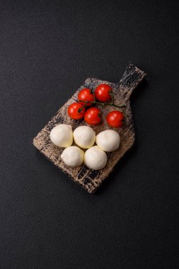 Lezzetli taze mozzarella peyniri domatesli, tuzlu ve baharatlı koyu beton arka planda.