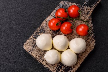 Lezzetli taze mozzarella peyniri domatesli, tuzlu ve baharatlı koyu beton arka planda.