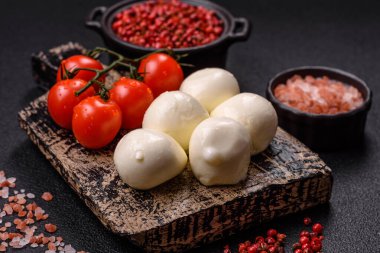 Lezzetli taze mozzarella peyniri domatesli, tuzlu ve baharatlı koyu beton arka planda.