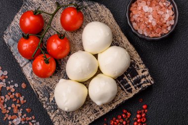 Lezzetli taze mozzarella peyniri domatesli, tuzlu ve baharatlı koyu beton arka planda.