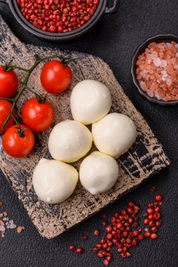 Lezzetli taze mozzarella peyniri domatesli, tuzlu ve baharatlı koyu beton arka planda.