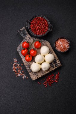 Lezzetli taze mozzarella peyniri domatesli, tuzlu ve baharatlı koyu beton arka planda.