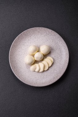 Lezzetli taze mozzarella peyniri domatesli, tuzlu ve baharatlı koyu beton arka planda.