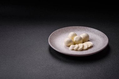 Lezzetli taze mozzarella peyniri domatesli, tuzlu ve baharatlı koyu beton arka planda.