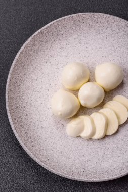 Lezzetli taze mozzarella peyniri domatesli, tuzlu ve baharatlı koyu beton arka planda.