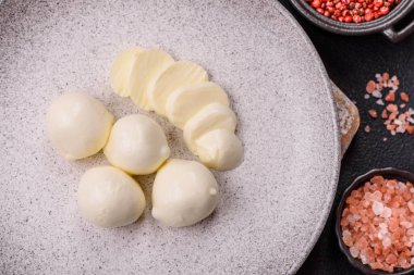 Lezzetli taze mozzarella peyniri domatesli, tuzlu ve baharatlı koyu beton arka planda.