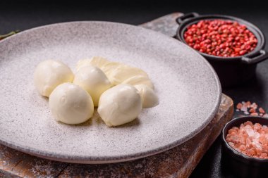 Lezzetli taze mozzarella peyniri domatesli, tuzlu ve baharatlı koyu beton arka planda.