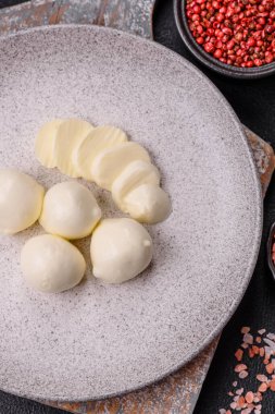 Lezzetli taze mozzarella peyniri domatesli, tuzlu ve baharatlı koyu beton arka planda.