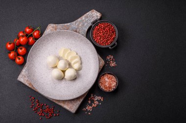 Lezzetli taze mozzarella peyniri domatesli, tuzlu ve baharatlı koyu beton arka planda.