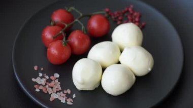 Lezzetli taze mozzarella peyniri domatesli, tuzlu ve baharatlı koyu beton arka planda.