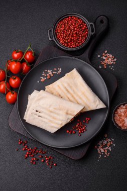 Pide, et, domates, peynir, sos, tuz ve baharatla birlikte koyu bir arkaplanda yuvarlan