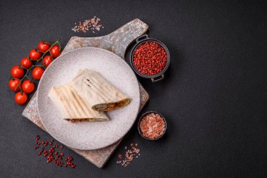 Pide, et, domates, peynir, sos, tuz ve baharatla birlikte koyu bir arkaplanda yuvarlan