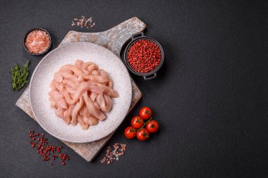 Çiğ tavuk filetosu, ahşap bir kesim tahtasının üzerinde baharat ve otlarla dilimlenmiş.