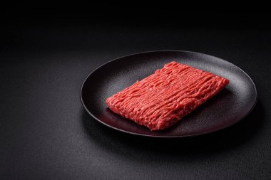 Koyu beton arka planda tuz, baharat ve otlu taze çiğ et.