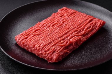 Koyu beton arka planda tuz, baharat ve otlu taze çiğ et.