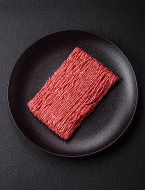 Koyu beton arka planda tuz, baharat ve otlu taze çiğ et.