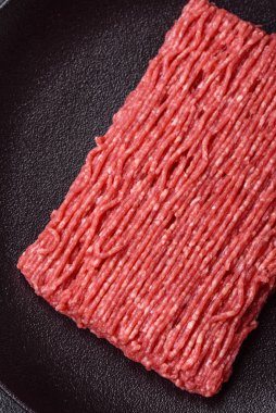 Koyu beton arka planda tuz, baharat ve otlu taze çiğ et.