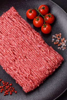 Koyu beton arka planda tuz, baharat ve otlu taze çiğ et.