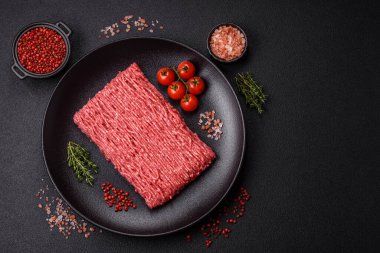 Koyu beton arka planda tuz, baharat ve otlu taze çiğ et.