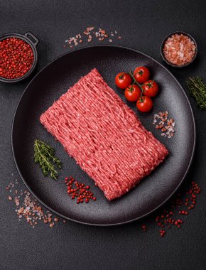 Koyu beton arka planda tuz, baharat ve otlu taze çiğ et.