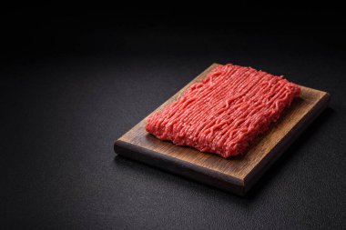 Koyu beton arka planda tuz, baharat ve otlu taze çiğ et.