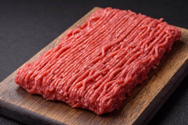 Koyu beton arka planda tuz, baharat ve otlu taze çiğ et.