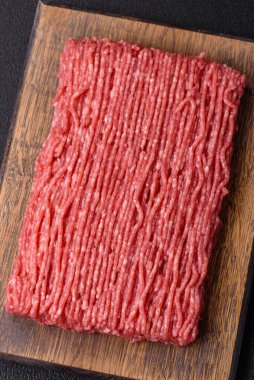 Koyu beton arka planda tuz, baharat ve otlu taze çiğ et.