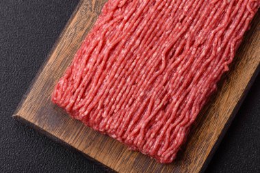 Koyu beton arka planda tuz, baharat ve otlu taze çiğ et.