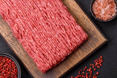 Koyu beton arka planda tuz, baharat ve otlu taze çiğ et.