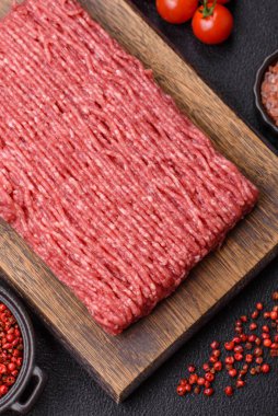 Koyu beton arka planda tuz, baharat ve otlu taze çiğ et.