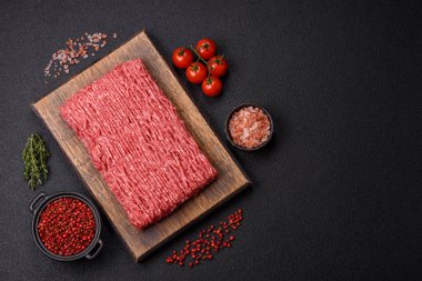 Koyu beton arka planda tuz, baharat ve otlu taze çiğ et.