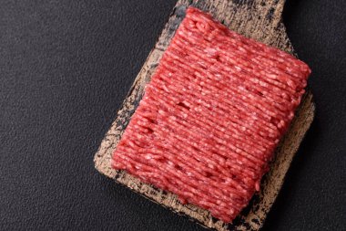 Koyu beton arka planda tuz, baharat ve otlu taze çiğ et.