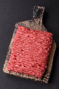 Koyu beton arka planda tuz, baharat ve otlu taze çiğ et.