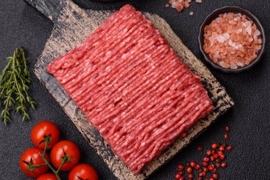 Koyu beton arka planda tuz, baharat ve otlu taze çiğ et.