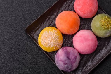 Lezzetli Asya mochi tatlısı pirinç hamuru kabuğu ve koyu beton arka planda meyveler.