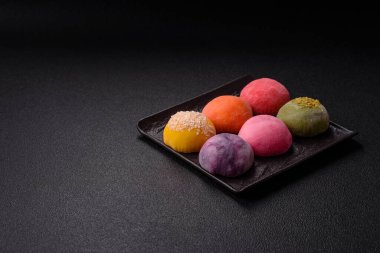 Lezzetli Asya mochi tatlısı pirinç hamuru kabuğu ve koyu beton arka planda meyveler.