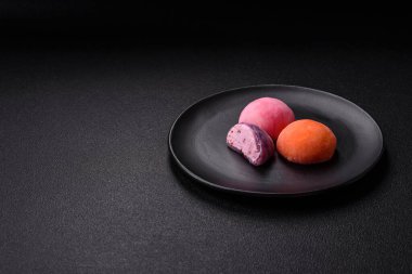 Lezzetli Asya mochi tatlısı pirinç hamuru kabuğu ve koyu beton arka planda meyveler.