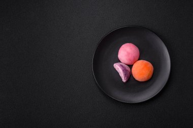 Lezzetli Asya mochi tatlısı pirinç hamuru kabuğu ve koyu beton arka planda meyveler.